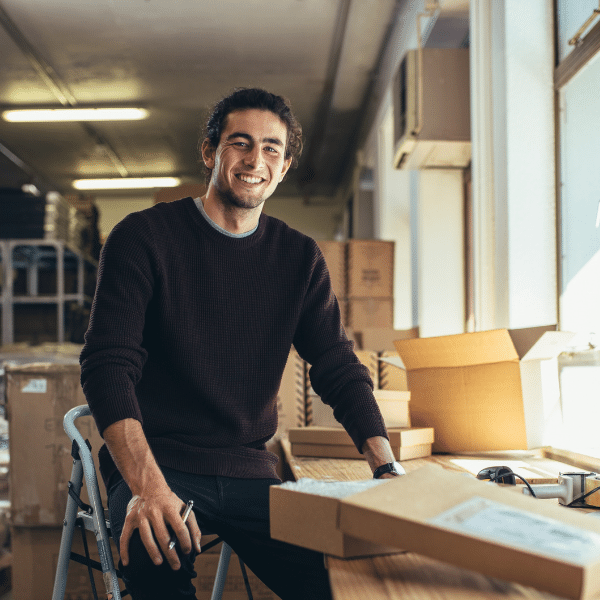 man sitting in warehouse sorting orders in boxes